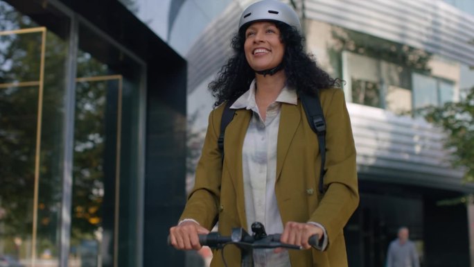一名戴着头盔骑着电动摩托车的女子在城市里
