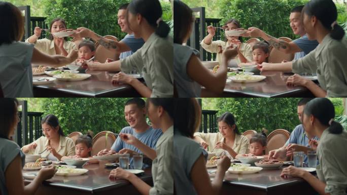 年轻的亚洲家庭吃着中国菜，坐在后院的餐桌上玩得很开心。多代同堂的家庭一起享受消费。