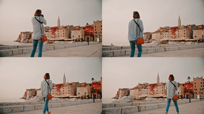 女游客在克罗地亚的海上码头探索罗维尼时拍摄老城区的后视图