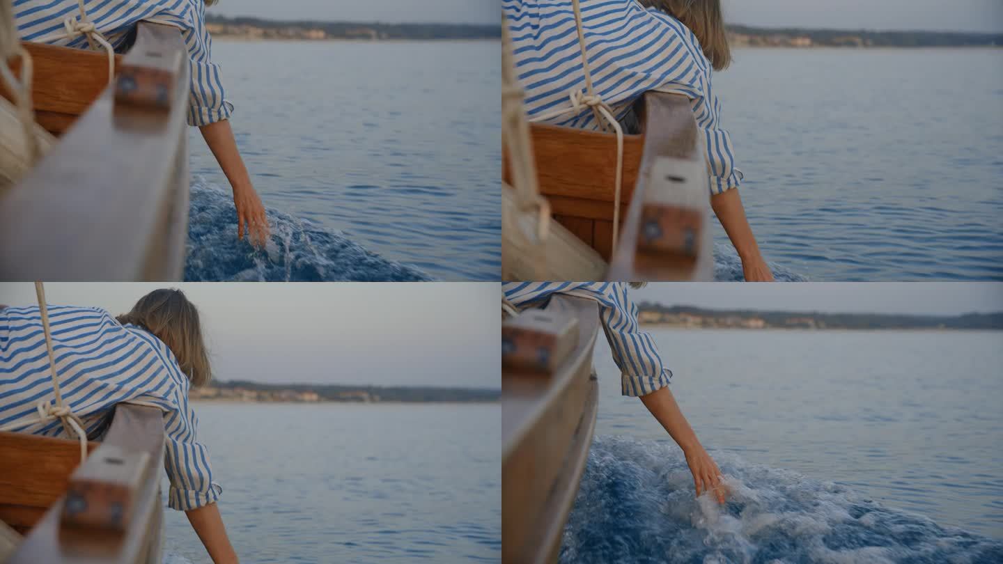 一名女子在黄昏航行时用手抚摸着水面