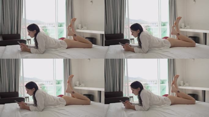 女人早上洗完澡后躺在床上玩智能手机