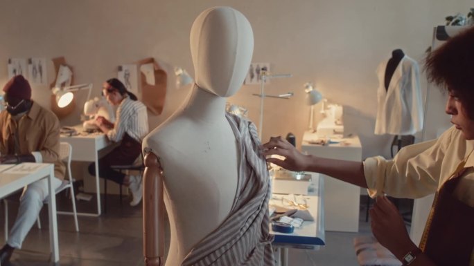 年轻的时装设计师创造礼服钉织物人体模型
