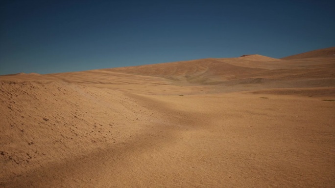 广阔的沙漠远景，以黄色的沙子为背景，深蓝色的天空。