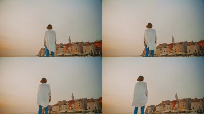 在克罗地亚罗维尼，女游客站在老城和广阔的天空的低角度镜头