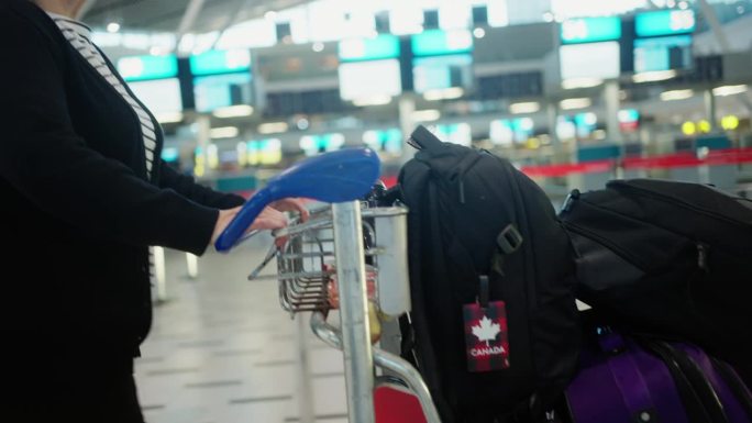一个成熟的女人在机场推车上推着她的行李