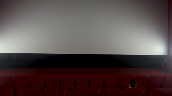 一个人坐在空荡荡的电影院大厅里
