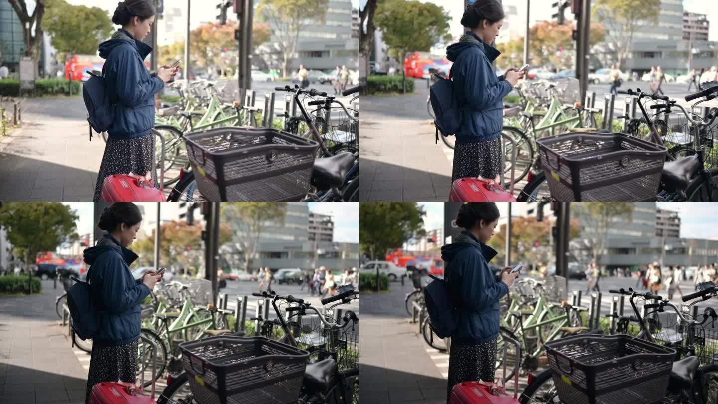 亚洲游客在日本京都街头使用手机应用程序租用共享单车