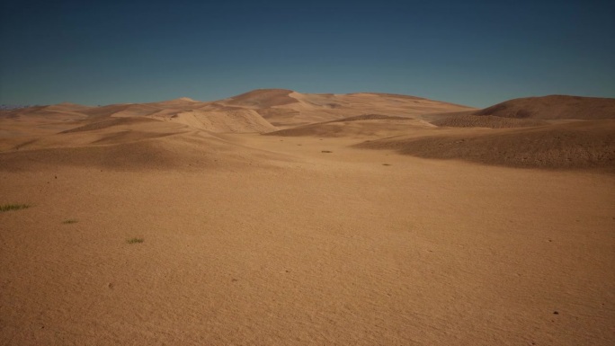 一望无际的沙漠景观，蓝天下的黄沙。