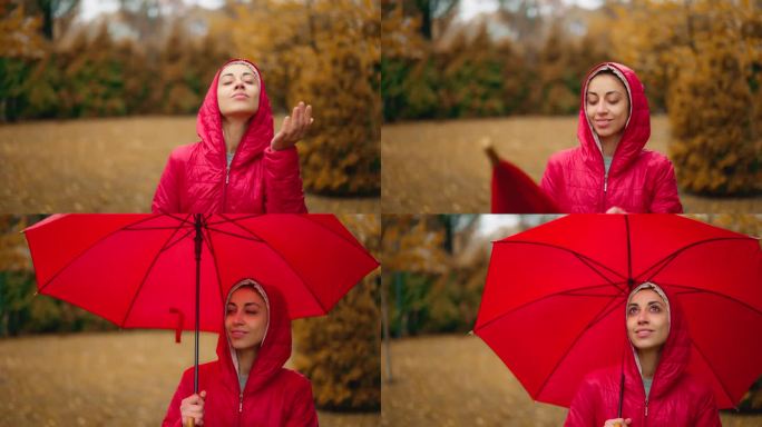 女孩脱下红色夹克连帽衫享受淅淅淅沥的雨，在城市公园撑起雨伞，仰望天空，享受雨滴洒在她脸上的微笑，感觉