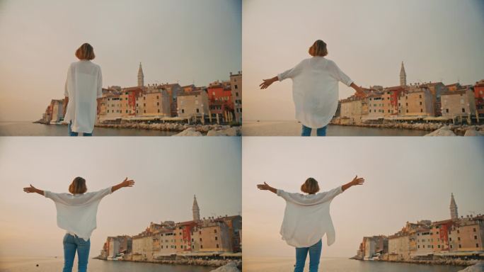 女游客伸开双臂，站在克罗地亚罗维尼的老城和晴朗的天空前