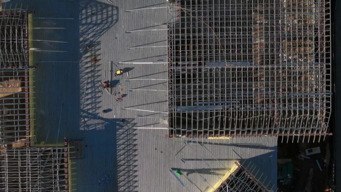工业屋顶的空中宽幅俯视图，屋顶工人在工业建筑或仓库上安装新屋顶。