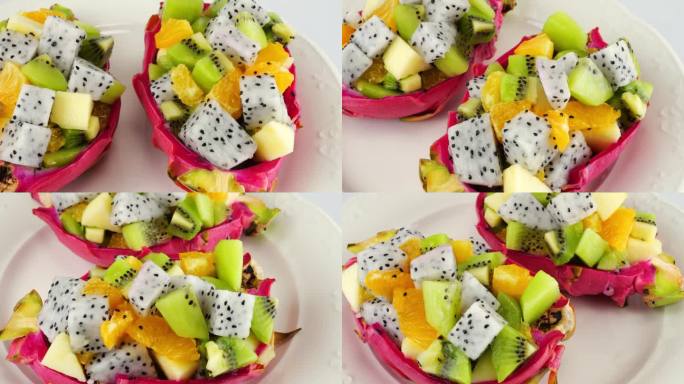 健康饮食排毒水果沙拉在果皮碗里，火龙果放在盘子里。一片桔子、猕猴桃、苹果。