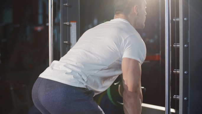肌肉健壮的白人男子在运动俱乐部用杠铃训练机锻炼