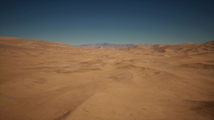 广阔的沙漠场景，赭色的沙子在无边无际的蓝天下伸展。