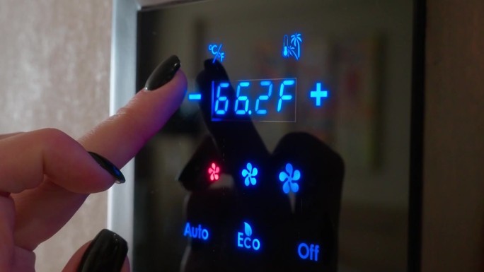 视频4 k。女孩用手指在房间墙壁上的电子面板上设置空调温度，以华氏度为单位。