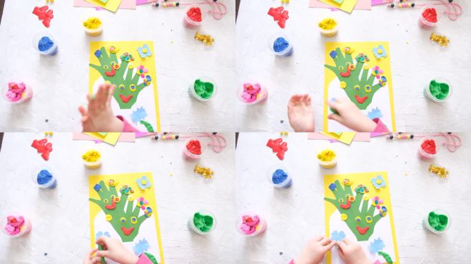 小女孩用五颜六色的粘土面团、橡皮泥和纸制作有趣可爱的贺卡。家庭教育。假期做准备。生日，母亲节，父亲节