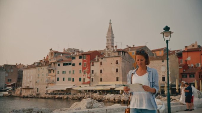 中年成年女游客拿着路线图，在克罗地亚罗维尼市的海上探索