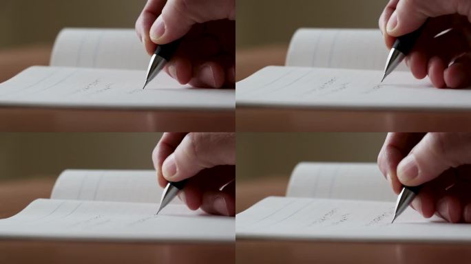 在笔记本上做笔记的人的手的侧视图
