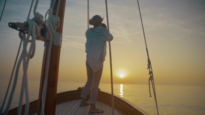 一个女人正在用双筒望远镜欣赏海上地平线上的日落