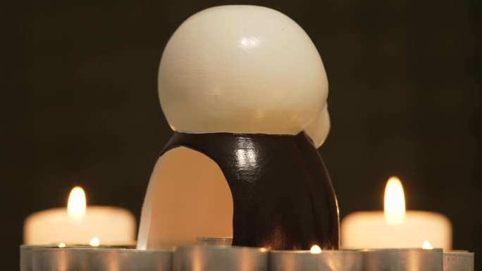 万圣节发光旋转骷髅骷髅头与黑色背景和燃烧的蜡烛