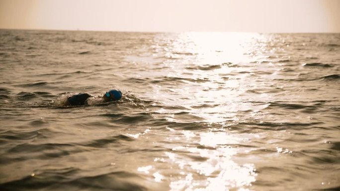 在日落时，女子在海景中对着天空游泳的镜头