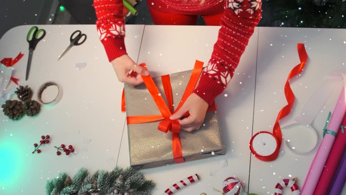 DIY包装，年轻女子美丽的双手在圣诞风格的桌子上的礼盒上系着整齐的蝴蝶结