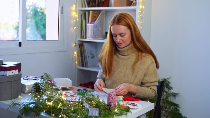 姜色女人用环保材料制作手工圣诞树玩具新年快乐装饰。装饰师为网上购物在商店销售创造礼物。女针线匠为家庭