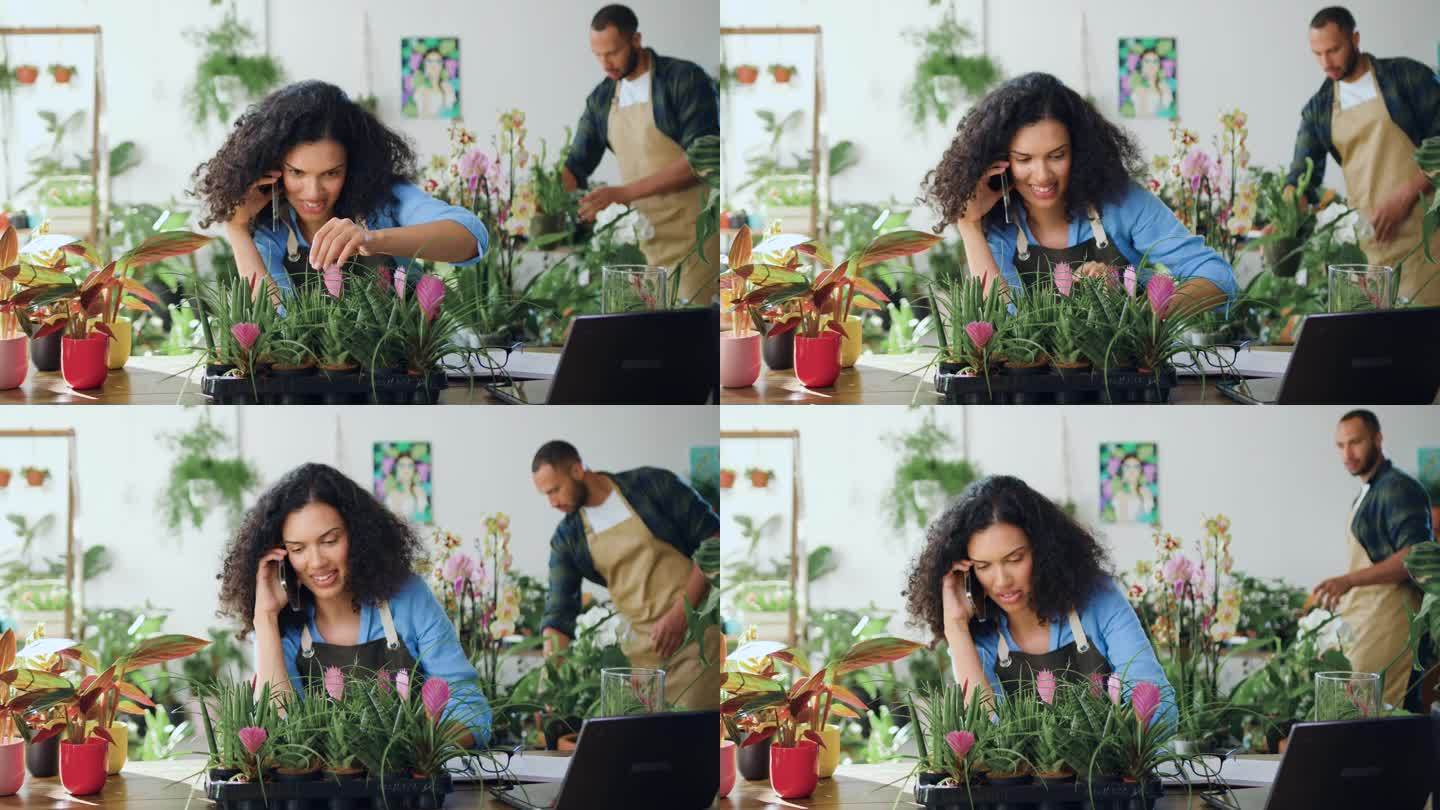 非裔美国花店女工，坐在桌边打电话，坐在舒适的花店里照顾植物。女花店老板在工作。小企业的概念。