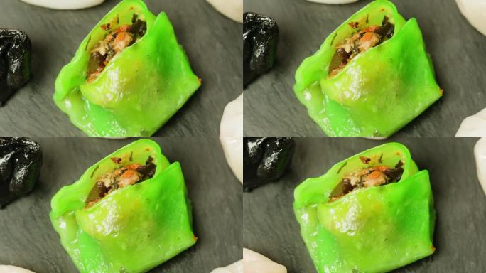 黑色盘子上的各种彩色点心特写特写。热气腾腾的技术。中国的甜点。点心配虾、鱼和肉。咖啡馆里的盘子。