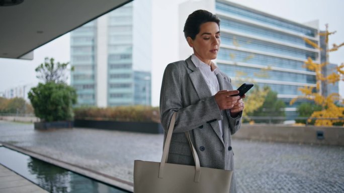 市中心一个女人在浏览智能手机，独自行走。深思熟虑的经理回答