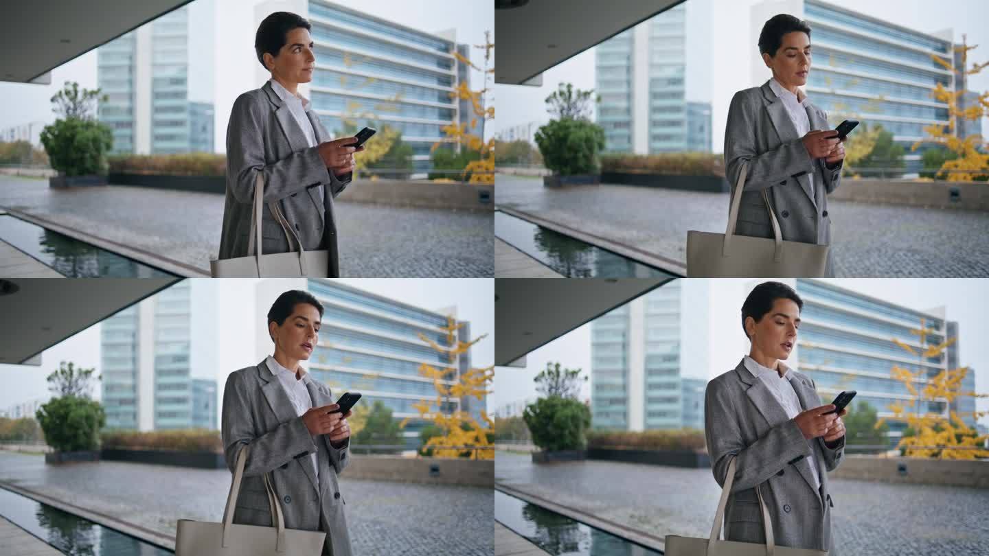市中心一个女人在浏览智能手机，独自行走。深思熟虑的经理回答