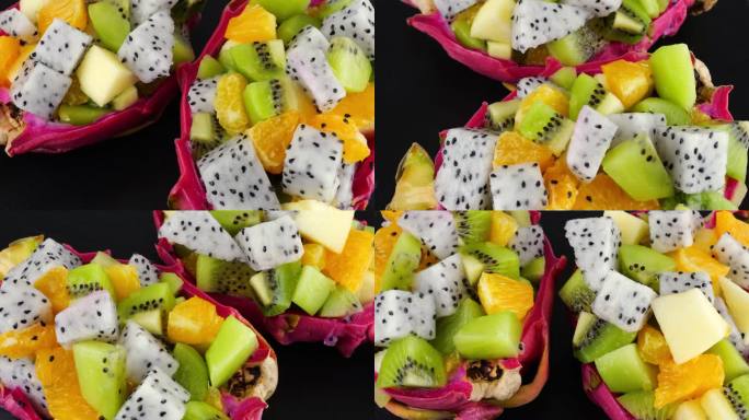 健康饮食排毒水果沙拉在皮碗的火龙果黑色石盘上。一片桔子、猕猴桃、苹果。