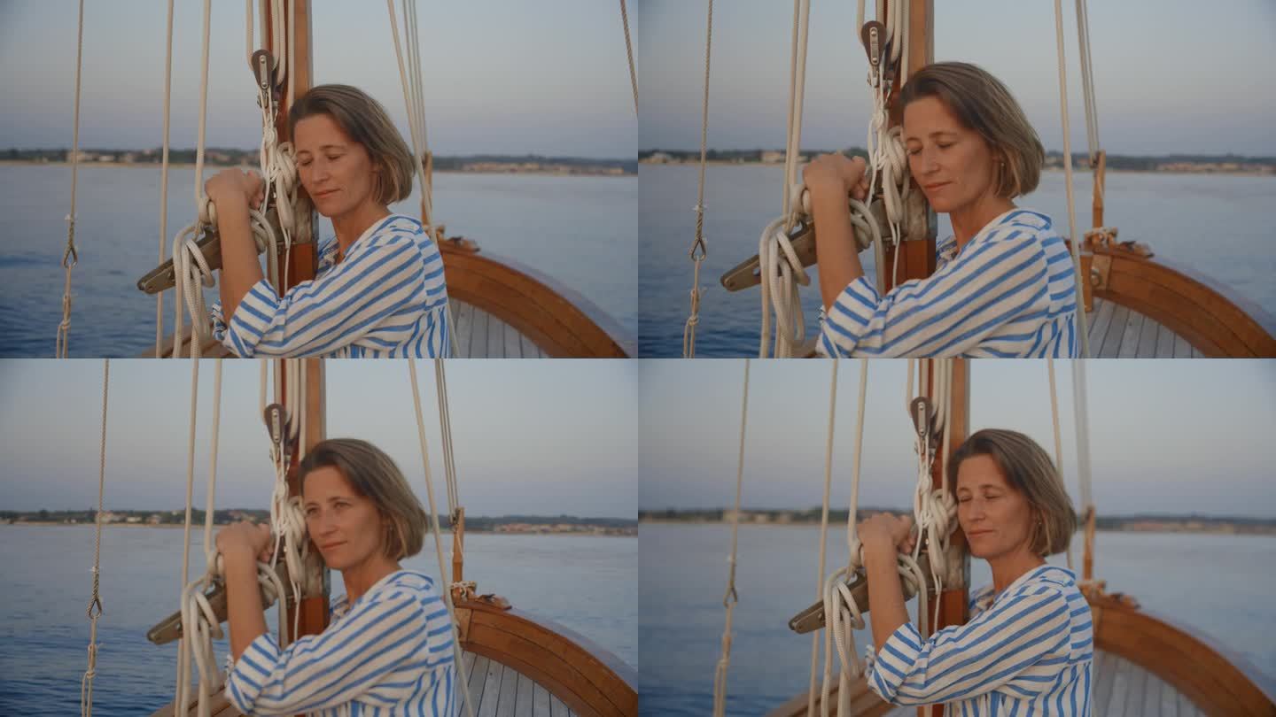 一名女子倚在桅杆上，在一艘帆船的甲板上享受这一刻