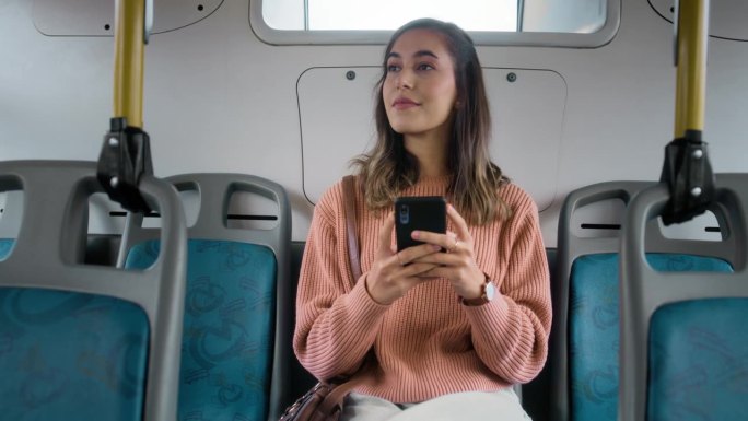 女性在公交车上使用手机和社交媒体，或者在城市通勤时开车时使用移动应用程序。公共交通，服务或乘车，女孩