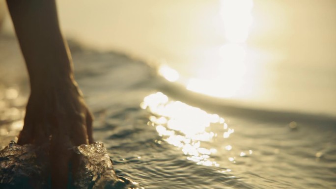 SLO莫优雅的飞溅:一个女人的手抚摸着水，而在日落航行
