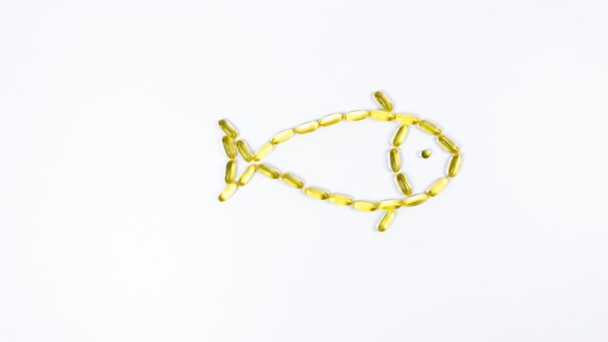鱼是由黄色透明鱼油胶囊制成的，欧米茄3通过移动鱼鳍和吹气泡来游泳。白色背景。