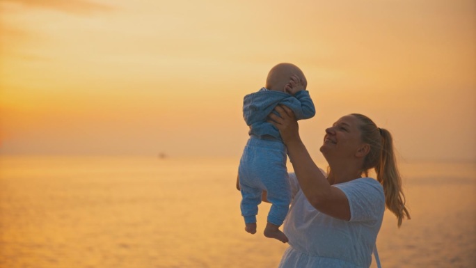 克罗地亚罗维尼老城，夕阳西下，一位兴高采烈的母亲坐在海边的岩石上抱着刚出生的婴儿