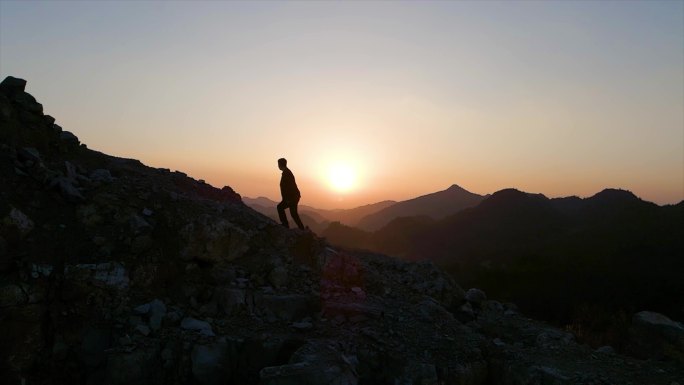 一个人从山顶漫步走下山人物剪影夕阳西下