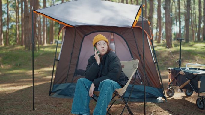 年轻的亚洲女游客在露营时使用手机，失去了信号。女性独自旅行和露营时混淆了电话、问题或信号差。网络问题