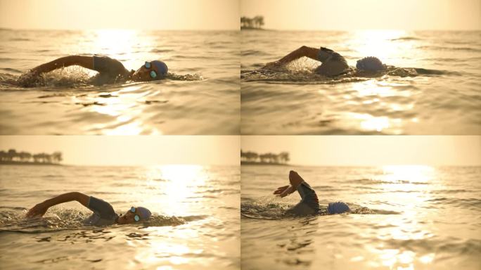 日落时，坚定的中年成年女子在海景中对着天空游泳的锁定镜头。开放水域游泳者