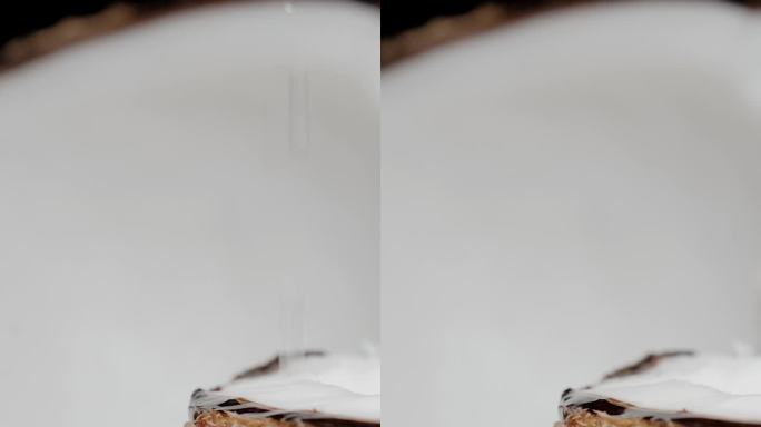 垂直视频。一个断成两半的椰子，汁液从上面滴下来。特写镜头，慢镜头。
