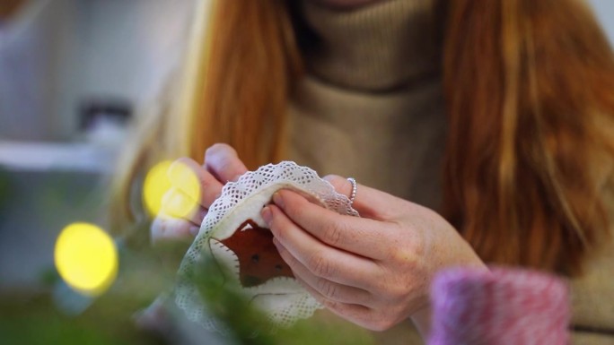 特写:红发女人亲手制作圣诞装饰品。手工工匠为家庭制作可爱的东西。新年假期DIY准备。冬季的业余爱好和