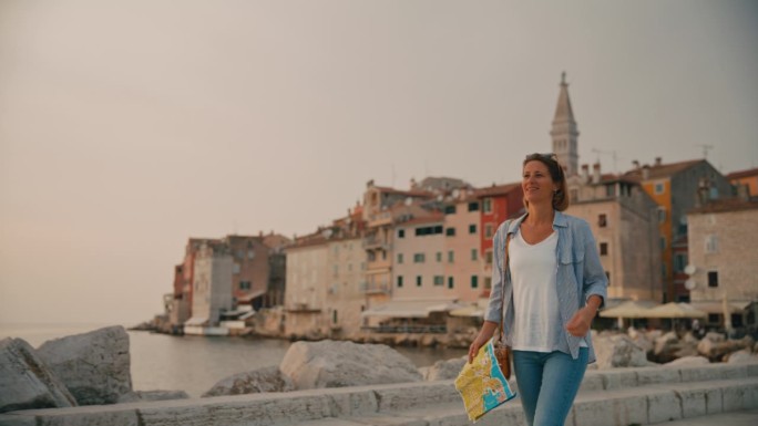 微笑的女游客拿着路线图，在克罗地亚的罗维尼市探索海路
