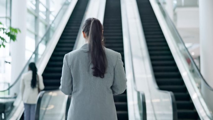 商务女性，在开会或进入办公大楼时步行和自动扶梯。商务人士在会议中心、机场或会议大厅的背部，用于专业工
