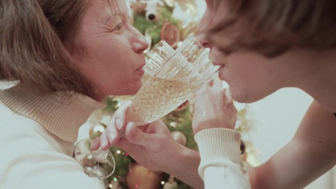 情侣用水晶高脚杯喝香槟，让我们为爱的镜头干杯，在装饰圣诞树的背景下为兄弟情谊干杯，选择性聚焦，模糊，