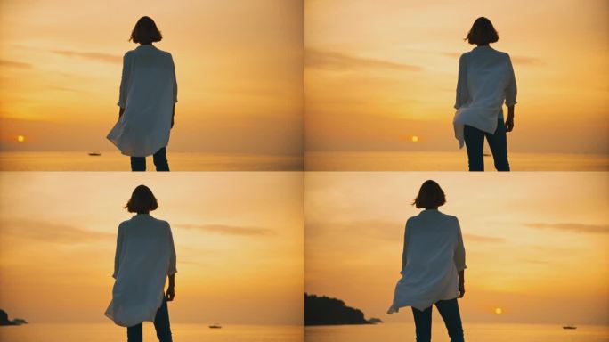 在克罗地亚罗维尼日落时，女游客站在大海上广阔的橙色天空的低角度视图