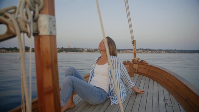 漂浮的宁静:一个女人享受着微风，在帆船的甲板上享受着这一刻