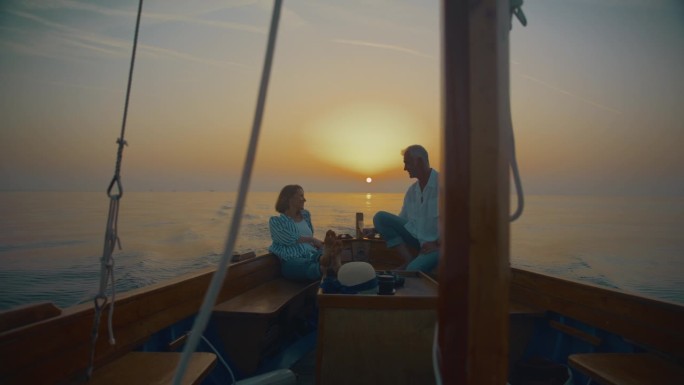 航行到日落的幸福:一对夫妇放松，交谈，珍惜这一刻