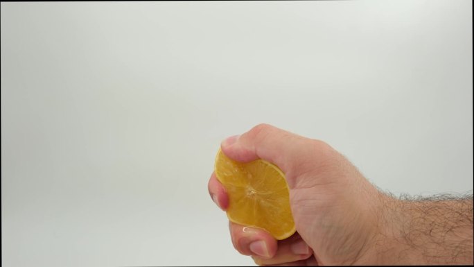 一名男子用手在白色背景上捏橘子
