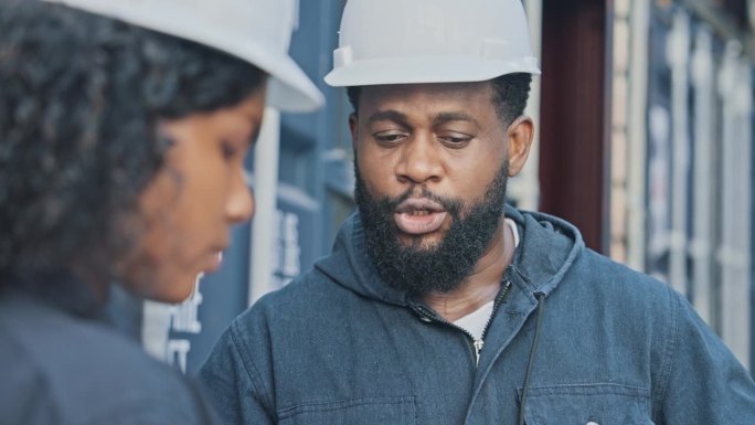 非裔美国工业工程师在集装箱码头与他的团队讨论